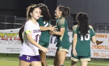 Columbia’s Sydney Rivas walks by as Lincoln players celebrate Nyla Close’s goal that triggered the mercy rule to finish off an 8-0 victory in the District 2-5A championship Wednesday night. (MORGAN MCMULLEN/Lake City Reporter)