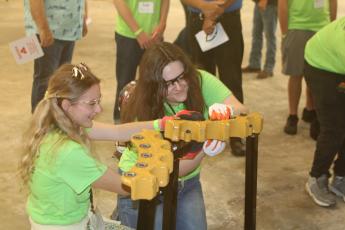 Stephanie Selman (from left) and Natalie Alessi, Fort White High School students, work on adding and removing bolts with an impact driver at the Ring Power vendor’s booth Wednesday morning at Build My Future. (TONY BRITT/Lake City Reporter)
