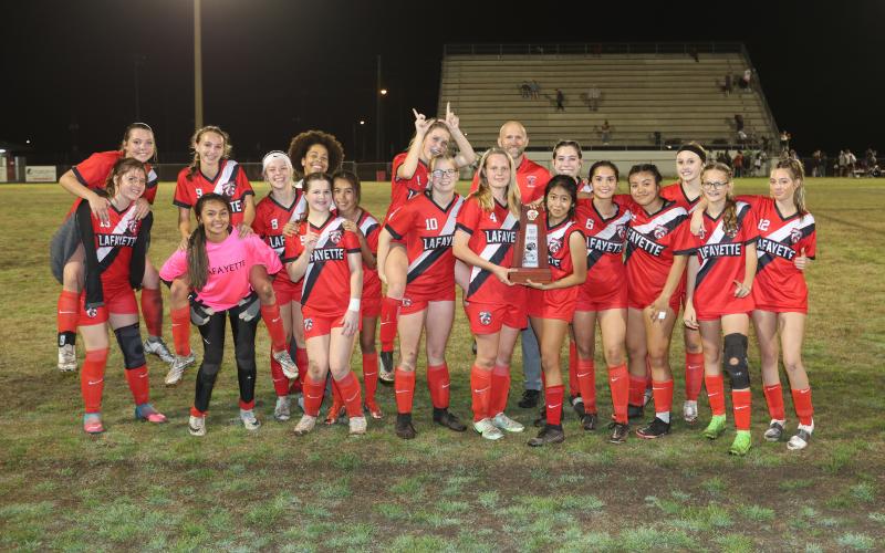 Lafayette’s girls soccer team celebrates with the District 2-2A trophy after defeating Bell 3-0 on Wednesday night. (PAUL BUCHANAN/Special to the Reporter)