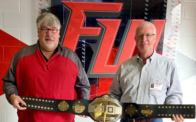 Fort White High School Principal Keith Couey (left) displays the championship belt alongside FDOT District Two Secretary Greg Evans. Fort White students increased their seatbelt wearing by 25% during the course of the competition. (COURTESY)