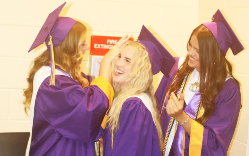 Ansley Williams (from left) adjusts Elle Grecian’s cap as Kansas Schrader also makes last minutes adjustments to Grecian’s outfit in the minutes leading up to Friday evening’s graduation at Columbia High School. (TONY BRITT/Lake City Reporter)