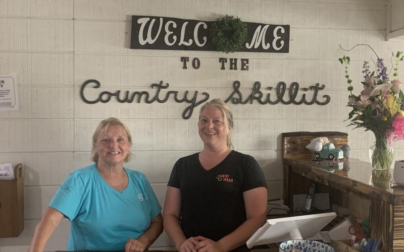 Pam DeLand (left) and assistant manager Stephanie Burgess pose near the entrance to Country Skillit in Lake City. The restaurant just moved to a site across from the Lake City Gateway Airport from Ellisville. (MORGAN MCMULLEN/Lake City Reporter)
